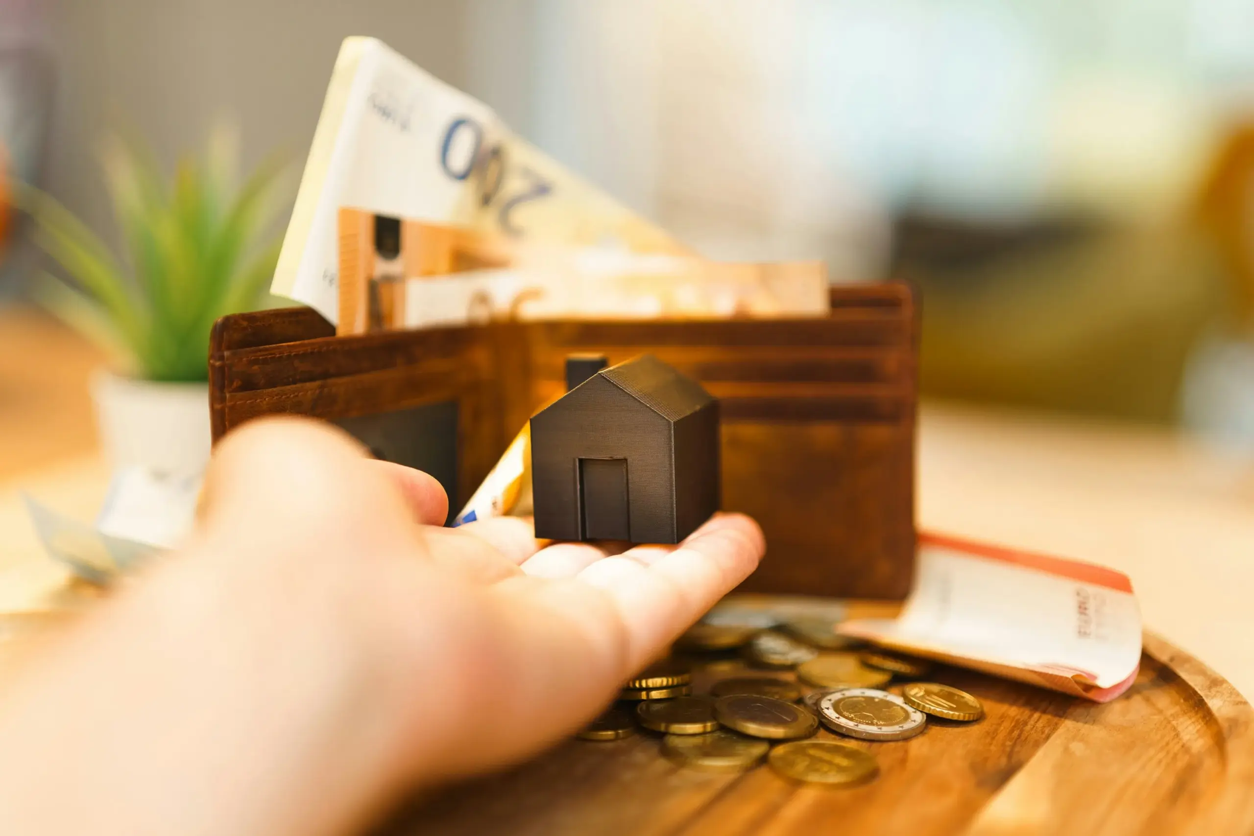 Geldbörse mit Hand die ein Haus hält